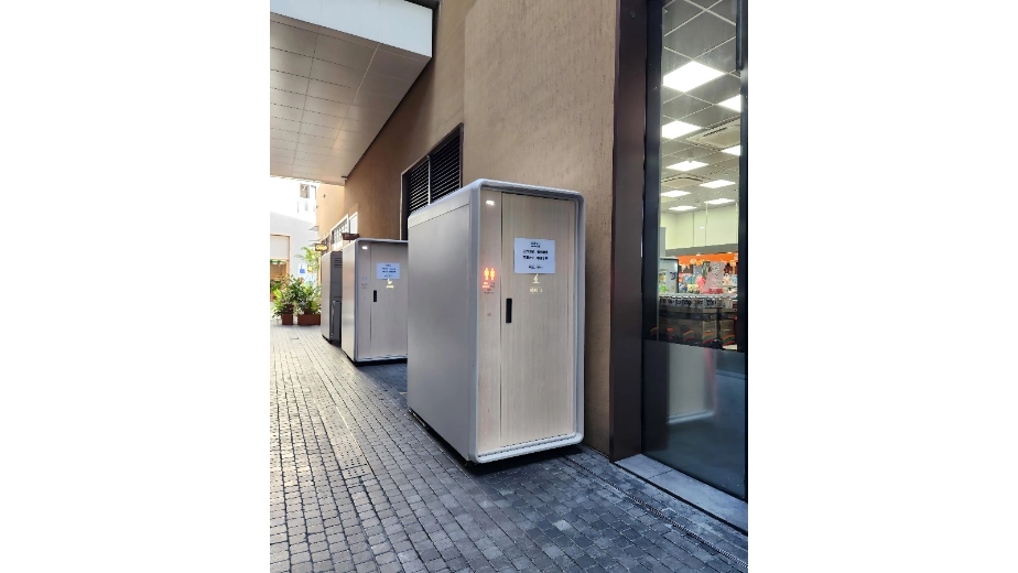 Factory-built public toilet modules beside a commercial building walkway