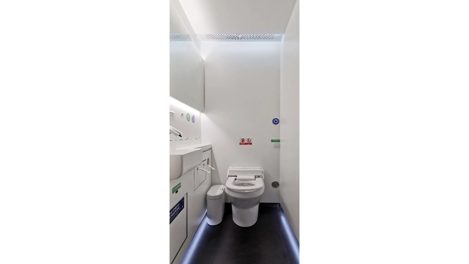 Seated-toilet interior with wash basin inside a modular public toilet unit